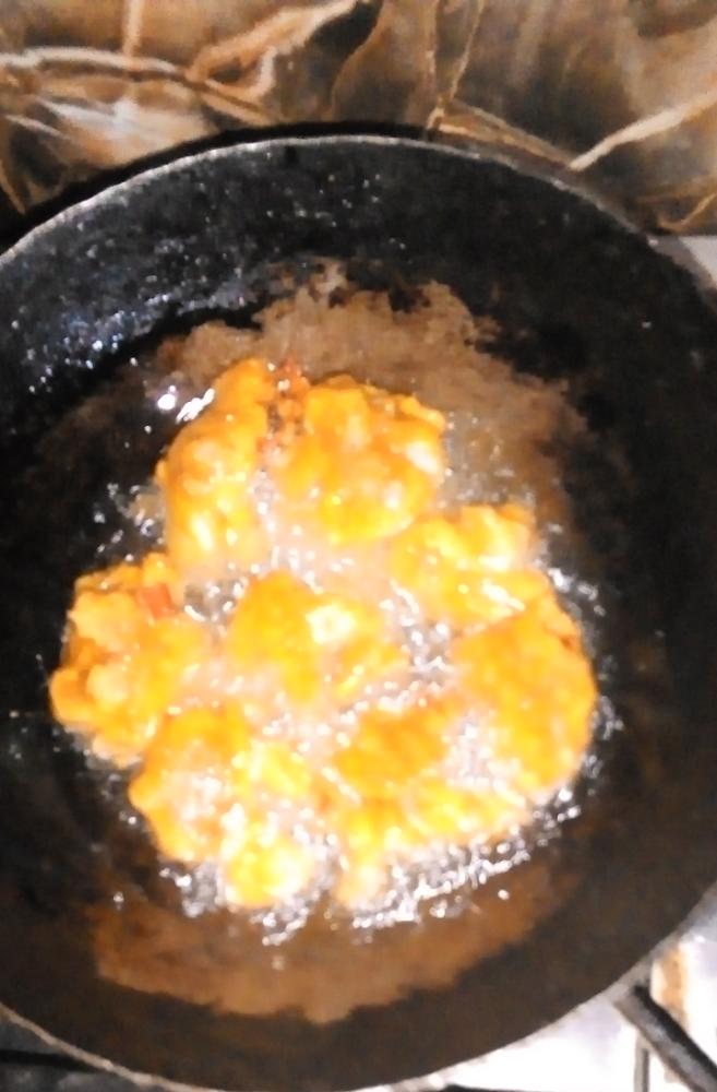 Real photograph of fresh dalvada frying in cast iron kadai with brass skimmer